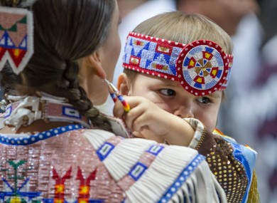 Omani Clairmont, age 2, pulls on his mother, Tanksi Clairmont's ear ring at the annual Gathering of Nations of North American native tribes.