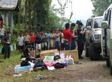 Residents watch as police inspect the contents of vehicles following the shooting.
