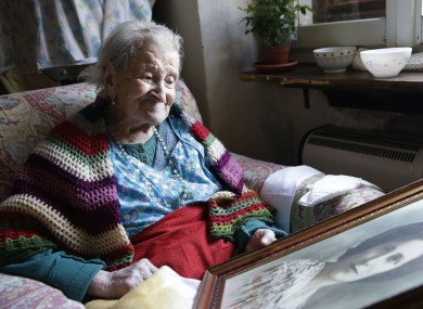 Emma Morano looks at an old portrait of herself in her apartment in Verbania, Italy.