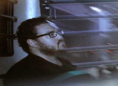 In this file photo taken through tinted glass, Rurik Jutting, a British banker, sits in a prison bus as he arrives at a court in Hong Kong.