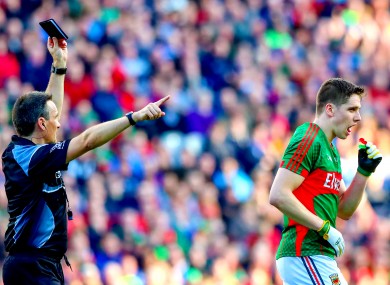 Referee Maurice Deegan shows Lee Keegan a black card.