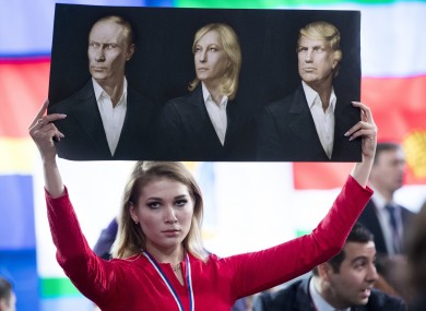 The holy trinity: A Russian journalist holds up portraits of Vladimir Putin, Marine Le Pen of France, and US president-elect Donald Trump in Moscow today.