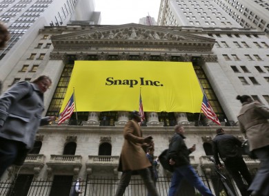People pass by the New York Stock Exchange after the banner for the Snap Inc. IPO was raised on the building's facade.