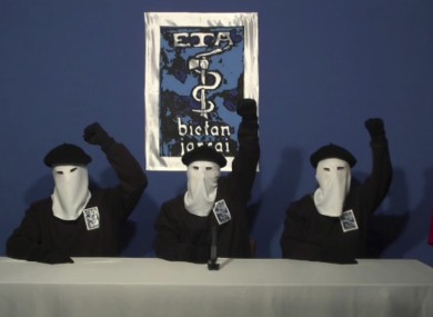 File: Masked members of the Basque separatist group ETA raise their fists in unison following a news conference at an unknown location.