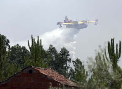A firefighting airplane drops its load of water trying to prevent a forest fire from reaching a rural Portuguese village earlier today.
