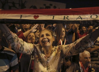 Iraqis celebrate in Tahrir square while holding national flags as they wait for the final announcement of the defeat of the Islamic state militants.