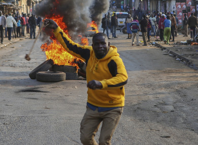 A man throws a stone towards police in Kibera, Nairobi, Kenya, as people block roads with stones to protest in support of Kenyan opposition leader and presidential candidate Raila Odinga.