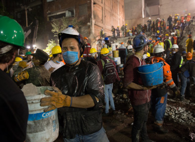 Volunteers and rescue workers remove rubble and search for survivors feared trapped in a collapsed building yesterday.