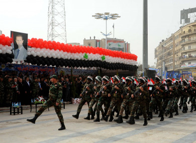 Syrian troops march past a portrait of Bashar al-Assad.