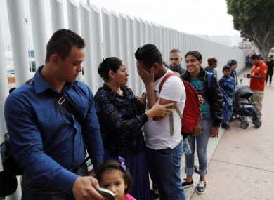 Calet Garcia, center in white shirt, of Honduras, cries once he realizes he will be able to apply for asylum in the U.S. with his friend Daisy Avelar, second from left, of El Salvador, Thursday, July 26, 2018, near the San Ysidro port of entry in Tijuana, Mexico
