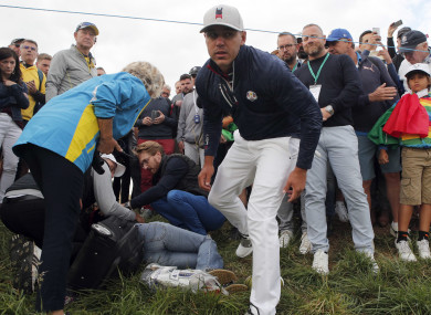 Brooks Koepka offers help to a spectator injured when his ball hit her on the 6th hole.
