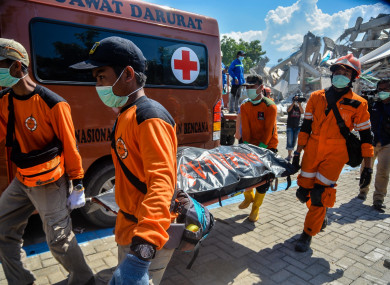 Rescue members transfer a body at a collapsed hotel in Palu, Central Sulawesi.