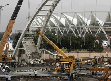 Construction workers clear the damage after a footbridge collapsed outside the main Commonwealth Games stadium yesterday.