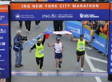 Edison Peña, flanked by two assistant runners, finishes the New York City Marathon to rapturous applause.