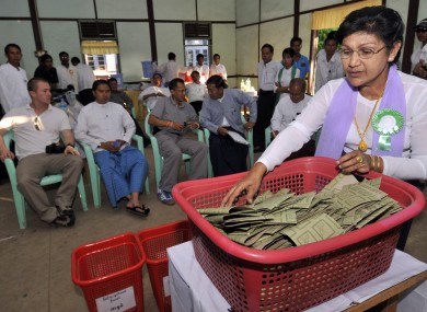 Journalists and foreign diplomatics on a poll monitoring tour watch as a polling official begins to count votes cast in yesterday's Burmese general election, the first since 1990.