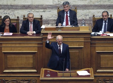 Greek Prime Minister George Papandreou waves his hand as his government's parliament members applaud after his speech in Athens