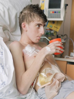 A young boy with Crohn's disease sitting up in hospital bed (image posed by model)
