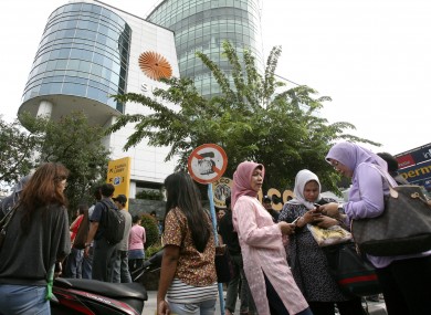 People wait as they are evacuated from a shopping mall after a strong earthquake was felt in Medan, Sumatra island, Indonesia.