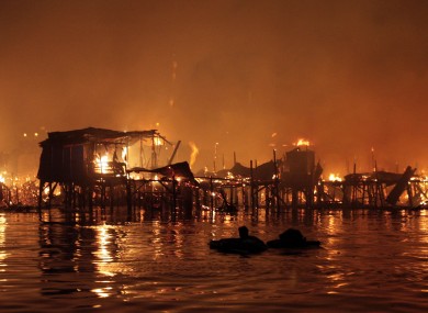 A man floats in the water as his neighbourhood - houses on stilts on the edge of a bay - went up in flames in Manila, the Philippines capital.