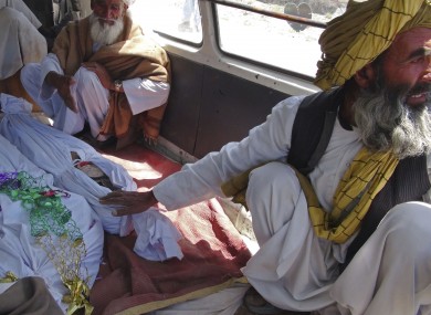Elderly men sit with the covered bodies of three children killed the strike