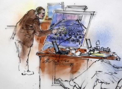 This courtroom sketch shows Aurora Police Detective Matthew Ingui pointing to a large photograph of the inside of the Century 16 theatre.