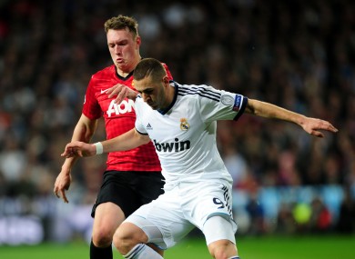 Manchester United's Phil Jones and Real Madrid's Karim Benzema (right) battle for the ball during the UEFA Champions League round of 16 match at Santiago Bernabeu.