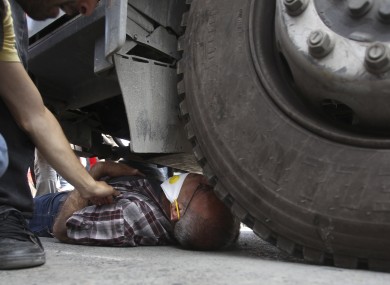 A protester lies under the wheel of a police water cannon vehicle.