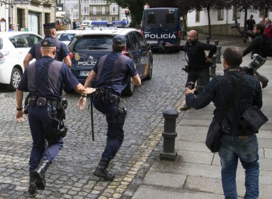 Media run after a police car carrying arrested train driver Francisco Jose Garzon Amo on Sunday