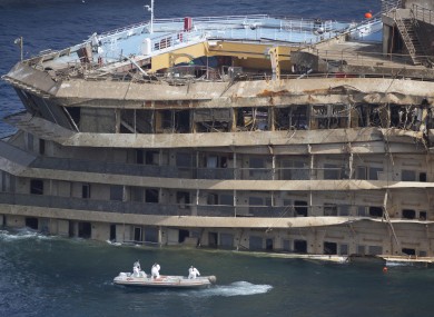 Workers on a boat sail past the Costa Concordia ship this week.