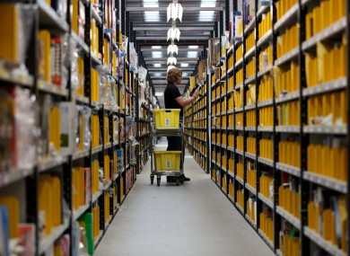 A worker selecting goods from racks in the Amazon fulfillment center in Peterborough, Cambridgeshire.
