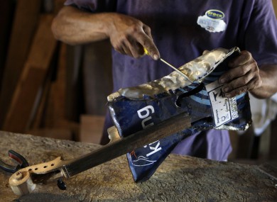 Nicolas Gomez makes a violin with recycled materials at his home in the Cateura.