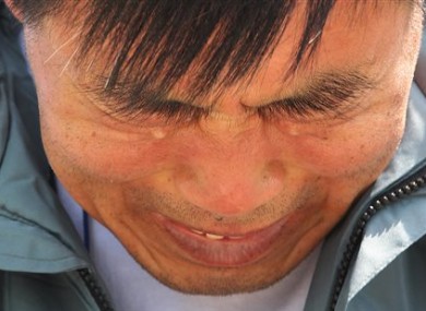 A relative of a passenger aboard the sunken ferry Sewol weeps as he waits for news on his missing loved one at a port in Jindo, South Korea.