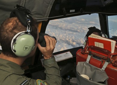 Flight Officer Stuart Doubleday uses binoculars on board a Royal Australian Air Force AP-3C Orion to scan for debris or wreckage of missing Malaysian Airlines flight.