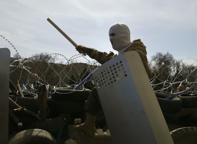 A masked man stands atop of a barricade at the regional administration building in in Donetsk.