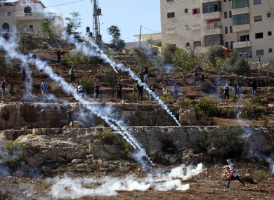 Palestinian protester runs from tear gas during clashes with security forces.