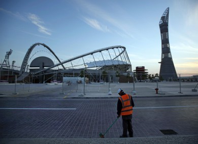 A worker cleans the road outside Khalifa sport complex in Doha, Qatar