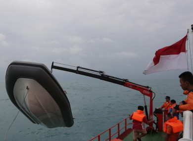 Members of the National Search And Rescue Agency (BASARNAS) unload a rubber boat from their ship.