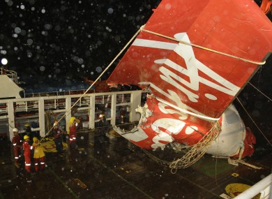 Crew members of Crest Onyx ship unload the wreckage of part of the ill-fated AirAsia Flight 8501 that crashed in the Java Sea