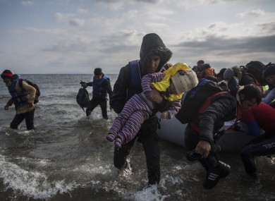 Migrants and refugees disembark from a dinghy after their arrival from Turkey on the Greek island of Lesbos on Saturday.