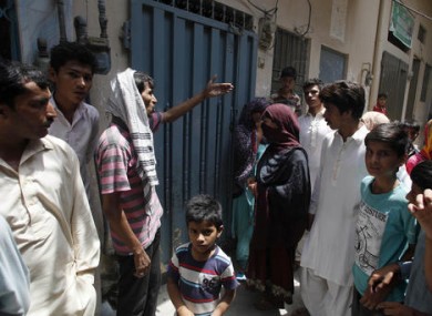 Local residents gather outside the home of Parveen Rafiq