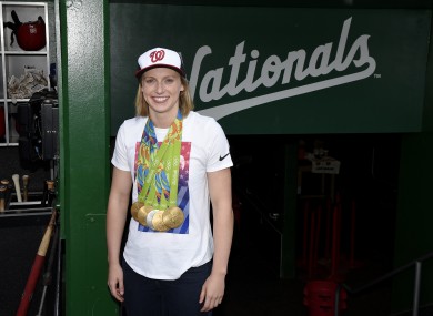 Olympic gold-medal swimmer Katie Ledecky poses with her medals in the dugout before a baseball game between the Baltimore Orioles and the Washington Nationals.