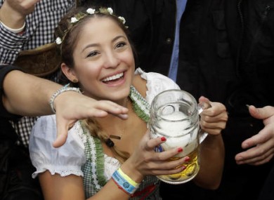 A young woman smiles with a beer during the opening of the 183rd Oktoberfest beer festival in Munich earlier today.