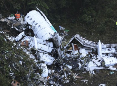 Rescue workers stand at the wreckage site of a chartered airplane that crashed outside Medellin, Colombia.