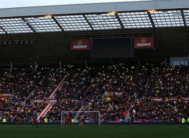 Fans hold their phones up as the stadium lights turn off during the Premier League match at the Stadium of Light.