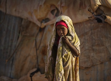 A young Somali girl stands outside her makeshift hut at a camp of people displaced from their homes elsewhere in the country by the drought, shortly after dawn in Qardho, Somalia.