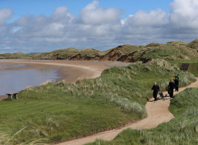 Golfers walk along the coastal path on the Doonbeg Golf Links course and hotel in Co Clare