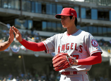 Shohei Ohtani #17 of the Los Angeles Angels high fives with a team mate.