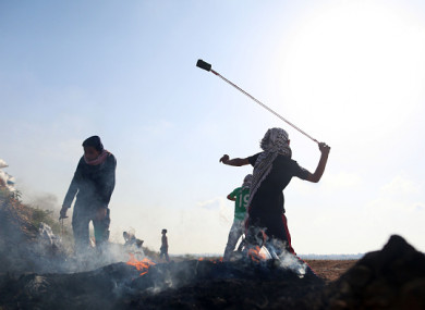 Palestinian demonstrators throw stones at Israeli soldiers near the fence during a protest on the Gaza Strip border with Israel.
