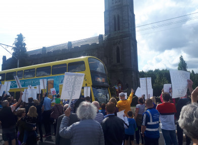 A bus and the march pass the church in the Chapelizod.
