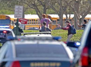 Students run with their hands in the air outside of Stoneman Douglas High School in Parkland
